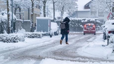 Eine Frau geht auf einer mit Schnee bedeckten Straße.