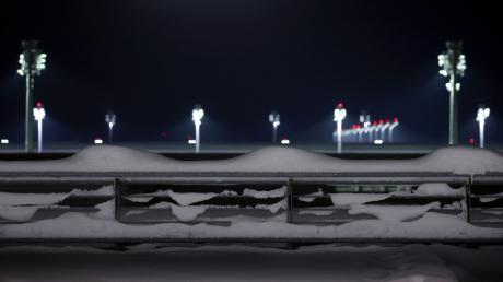 Flutlichter stehen hinter einem schneebedeckten Parkhaus am Münchener Flughafen.