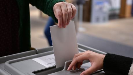 Ein Wähler steckt seinen Wahlzettel in eine Urne.