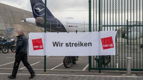 „Wir streiken“ steht auf einem Plakat an einem Tor des Flughafens Frankfurt. Die Gewerkschaft Verdi hat das Lufthansa-Bodenpersonal erneut zu einem Warnstreik aufgerufen.