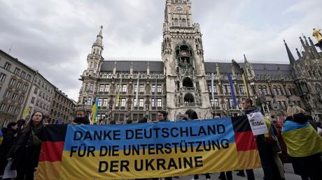 Teilnehmer einer Kundgebung anlässlich des zweiten Jahrestags des russischen Angriffskriegs auf die Ukraine stehen mit einem Banner «Danke Deutschland für die Unterstützung der Ukraine» auf dem Marienplatz.