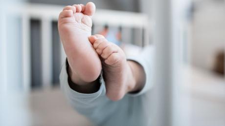 Die Füße eines Babys sind in einem Kinderbett zu sehen.