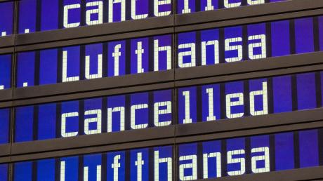 Anzeigentafeln zeigen «cancelled» und «Lufthansa» am Flughafen München an.