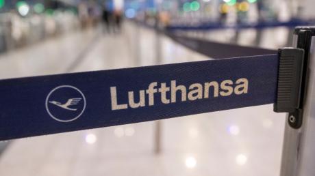 Das Logo der Lufthansa ist auf einem Absperrband am Check-In am Flughafen zu sehen.