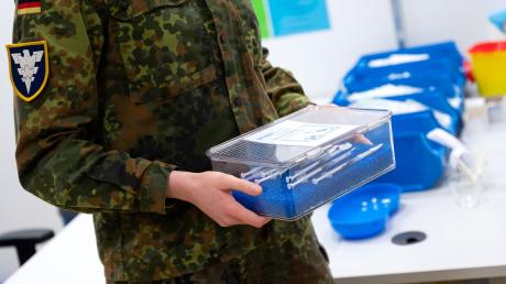 Eine Soldatin der Bundeswehr trägt im Impfzentrum eine Kiste mit Spritzen gegen das Coronavirus (Biontech).