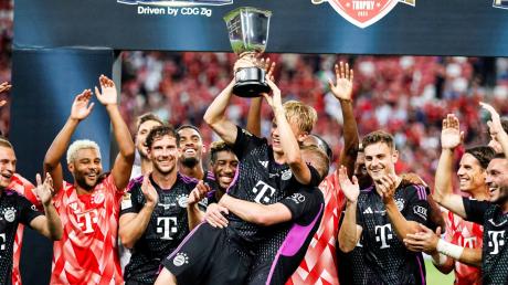 Frans Krätzig (M) hält den Pokal. Der FC Bayern reist im Sommer wieder nach Asien.
