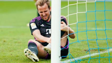 Harry Kane von München sitzt mit schmerzverzerrtem Gesicht auf dem Rasen. Er will gegen Dortmund spielen.