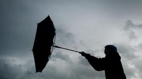 Von einer Windböe erfasst wird der Regenschirm eines Spaziergängers.