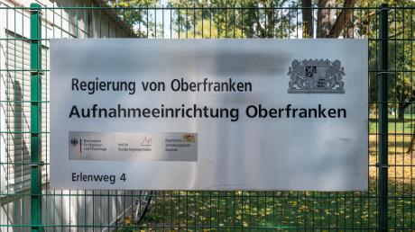Ein Hinweisschild der Aufnahmeeinrichtung Oberfranken hängt am Zaun der Flüchtlingsunterkunft.