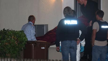 Eine Leiche wird aus einem Mehrfamilienhaus getragen in dem drei Menschen erschossen wurden.