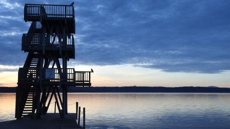 Im Sonnenaufgang steht der hölzerne Sprungturm des Strandbades am Ammersee.