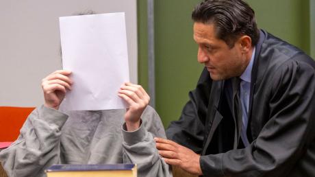 Ein 21-Jähriger Mann, der seine Mutter mit einer Axt erschlagen haben soll, unterhält sich im Gerichtssaal des Landgericht München I mit seinem Anwalt Ömer Sahinci (r).