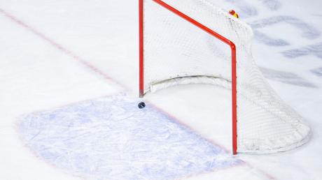 Ein Puck fliegt in ein leeres Eishockey-Tor.