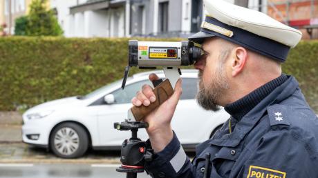 Ein Polizeibeamter schaut durch ein Messgerät zur Geschwindigkeitskontrolle.