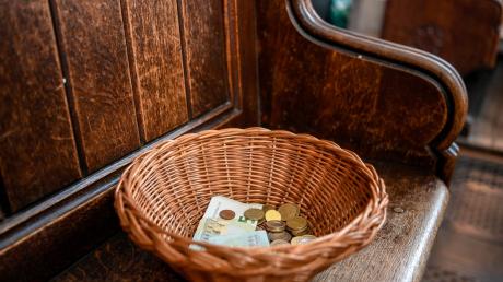 Ein Korb mit Geldscheinen und Münzen steht in einer Kirche.
