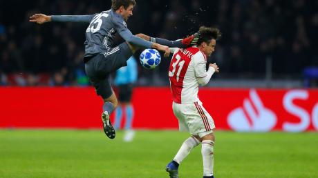 Bayerns Thomas Müller trifft Ajaxs Nicolas Tagliafico (r) mit seinem Fuß am Kopf.