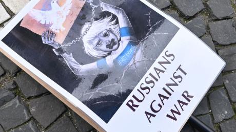 Ein Schild mit der Aufschrift «Russians against war» liegt auf dem Odeonsplatz in München auf dem Boden.