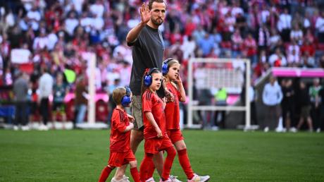 Münchens Harry Kane geht mit Kindern nach dem Spiel auf dem Spielfeld.
