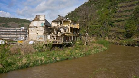 Ein abbruchreifes Haus, das durch die Flut zerstört wurde, steht an einem Ufer.