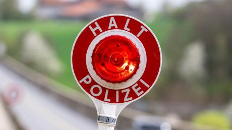 Eine Kelle mit der Aufschrift "Halt Polizei" wird während einer Verkehrskontrolle hochgehalten.