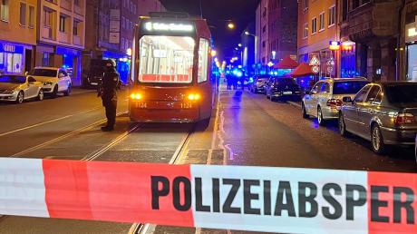 Ein Polizist steht mit einer Maschinenpistole neben einer Straßenbahn hinter einer Polizeiabsperrung. Bei Schüssen in der Nürnberger Südstadt war Ende Oktober 2022 ein Mann gestorben und ein weiterer schwer verletzt worden.