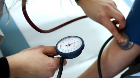 ILLUSTRATION - Einem Menschen wird in einer Arztpraxis der Bluthochdruck gemessen.