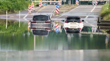 Zwei Autos stehen unter einer Saarbrücke im Stadtteil Schönbach im Hochwasser.