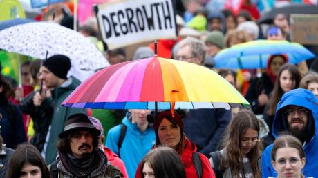 Zahlreiche Menschen nehmen auf dem Königsplatz an einer Demonstration zum Klimastreik teil und halten ein Plakat mit der Aufschrift „DEGROWTH“ in die Höhe.