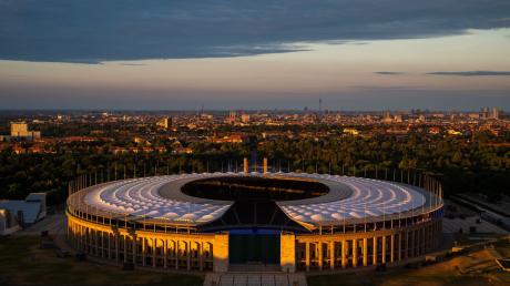 Die untergehende Sonne scheint auf das Olympiastadion in Berlin.