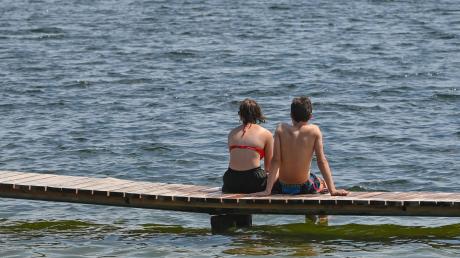 Zwei Personen sitzen auf einem Steg am Storkower See.
