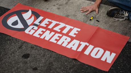 Ein Aktivist der Gruppe "Letzte Generation" blockiert eine Kreuzung.