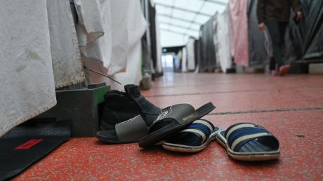 Schuhe einer Flüchtlingsfamilie sind in einem Zelt der Flüchtlingsunterkunft vor einer Wohnparzelle abgestellt.