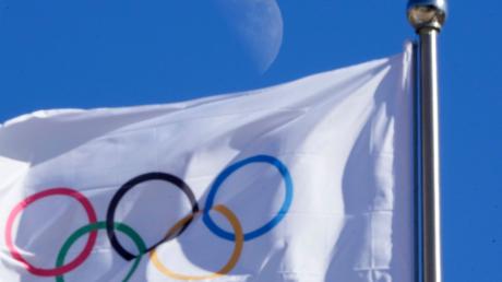 Eine olympischen Flagge weht vor blauem Himmel im Wind.