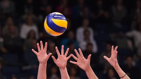 Hände greifen nach einem Volleyball.