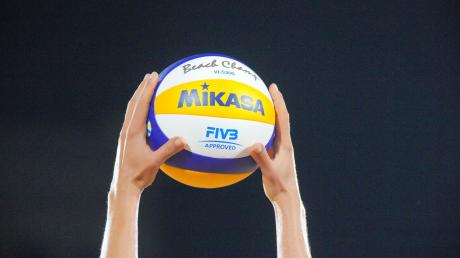 Ein Volleyball wird mit beiden Händen nach oben gehalten.