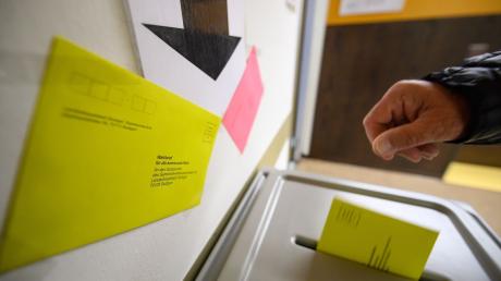 Ein Mann wirft einen Wahlbrief für die Kommunalwahl in Baden-Württemberg in eine Wahlurne.