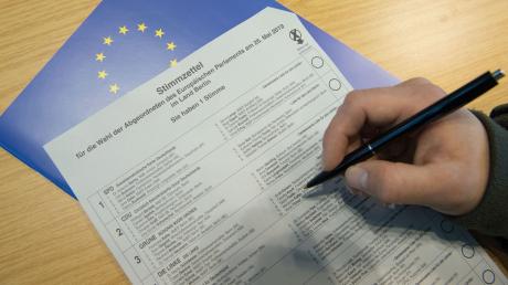Eine Hand hält einen Stift in der Briefwahlstelle des Bezirks Berlin-Mitte über einen Stimmzettel zur Europawahl 2019.