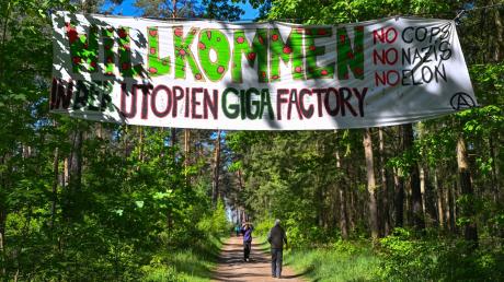 Aktivisten der Initiative «Tesla stoppen» haben in einem Wald nahe dem Werk der Tesla-Gigafactory Berlin-Brandenburg ein Transparent mit der Aufschrift «Willkommen in der Utopien Giga Factory No Cops, No Nazis, No Elon» aufgehängt.