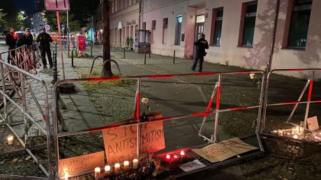 Brennende Kerzen stehen vor Schildern mit der Aufschrift «Stop Antisemitismus» an dem abgesperrten Bürgersteig.