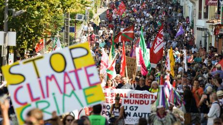 Demonstranten marschieren in Hendaye mit Flaggen und Plakaten während eines Protests gegen den G7-Gipfel.
