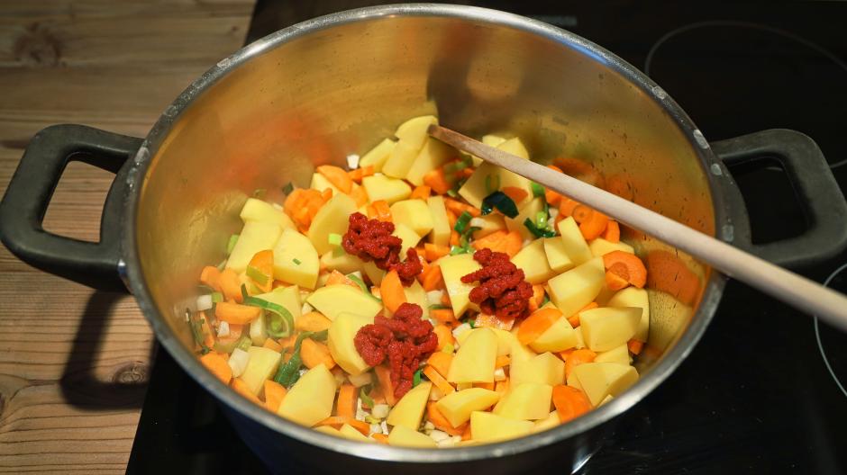 Fry the potatoes, carrots, leeks and celery with 3 tablespoons of tomato paste.