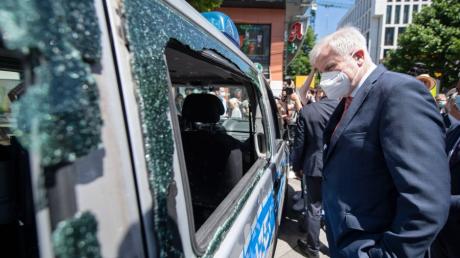 Bundesinnenminister Horst Seehofer betrachtet nach der Krawallnacht von Stuttgart ein beschädigtes Polizeiauto.