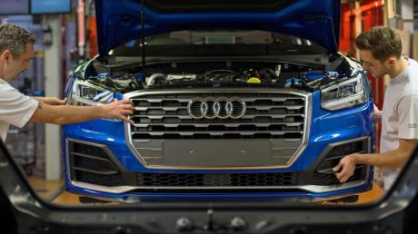Fertigungsmechaniker bringen an einem Fließband im Audi-Werk die Front an einem Audi an.