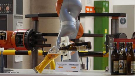Der sensitive Leichtbauroboter LBR iiwa für eine sichere Mensch-Roboter-Kollaboration schenkt ein Weißbier ein.