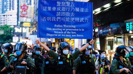 Ein Polizist warnt Demonstranten: „Löst euch auf, oder wir wenden Gewalt an.“ In Hongkong richten sich Proteste gegen ein Sicherheitsgesetz. 	