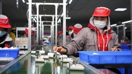 Menschen arbeiten in einer Fabrik am Fließband. Bei dem neuen Gesetz geht es auch um die Vermeidung von Ausbeutung und Kinderarbeit in weltweiten Lieferketten.