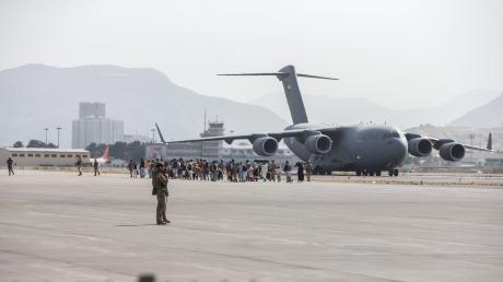 Familien werden für deren Evakuierung zu einer Boeing C-17 auf dem Flughafen Kabul geleitet.