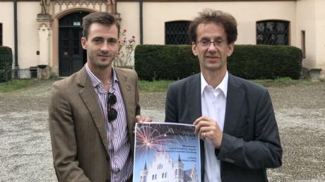 Michael Freiherr von Freyberg-Eisenberg (links) und Bernhard Löffler präsentieren ein kleines Plakat, das den Konzertabend auf Schloss Haldenwang bewirbt.