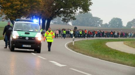 An einem Fußmarsch setzen sich gLange Schlange auf freier Strecke zwischen Bergen und Aulzhausen, gesichert von mehrerern Polizeifahrzeugen, Einsatzleiter war der Dienststellenleiter aus Aichach, Michael Jakob.