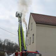 Aus dem Kamin der Jedesheimer Grundschule steigt schwarzer Rauch auf. Die Feuerwehr ist mit der Drehleiter im Einsatz.